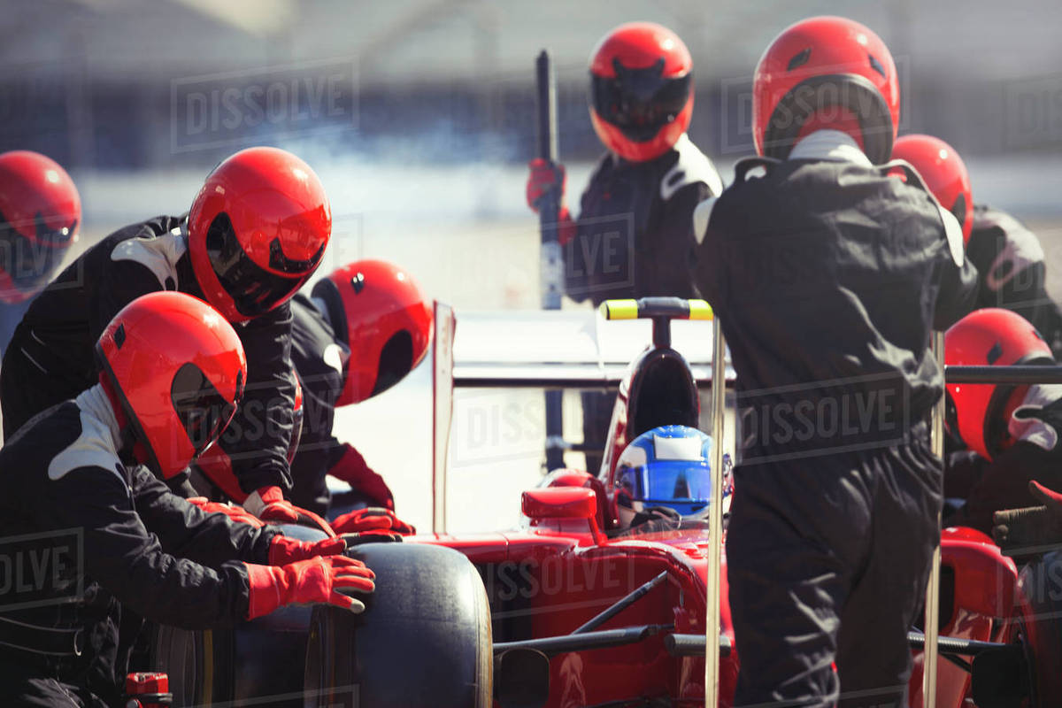 Pit crew replacing tires on formula one race car in pit lane Royalty-free stock photo