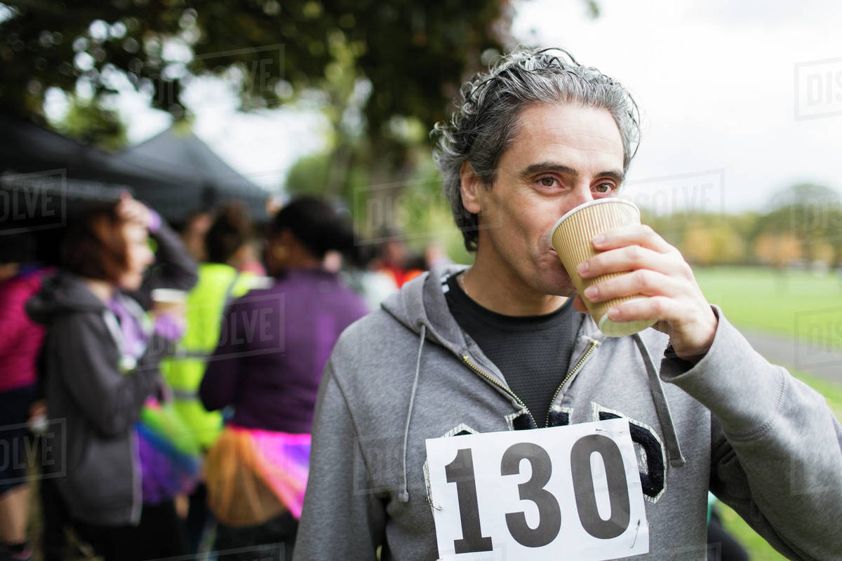 Male marathon runner drinking water in park Stock Photo Dissolve