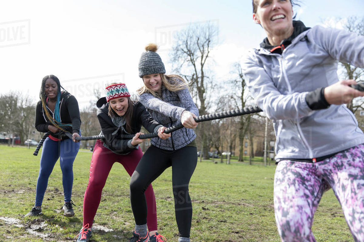 Determined women pulling rope in tugofwar in sunny park Stock Photo