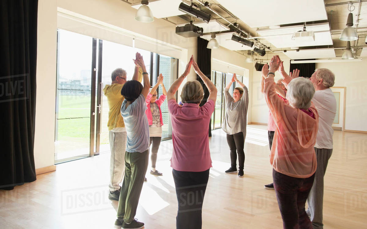 Active seniors exercising, stretching arms overhead in Active seniors exercising, stretching arms overhead in
