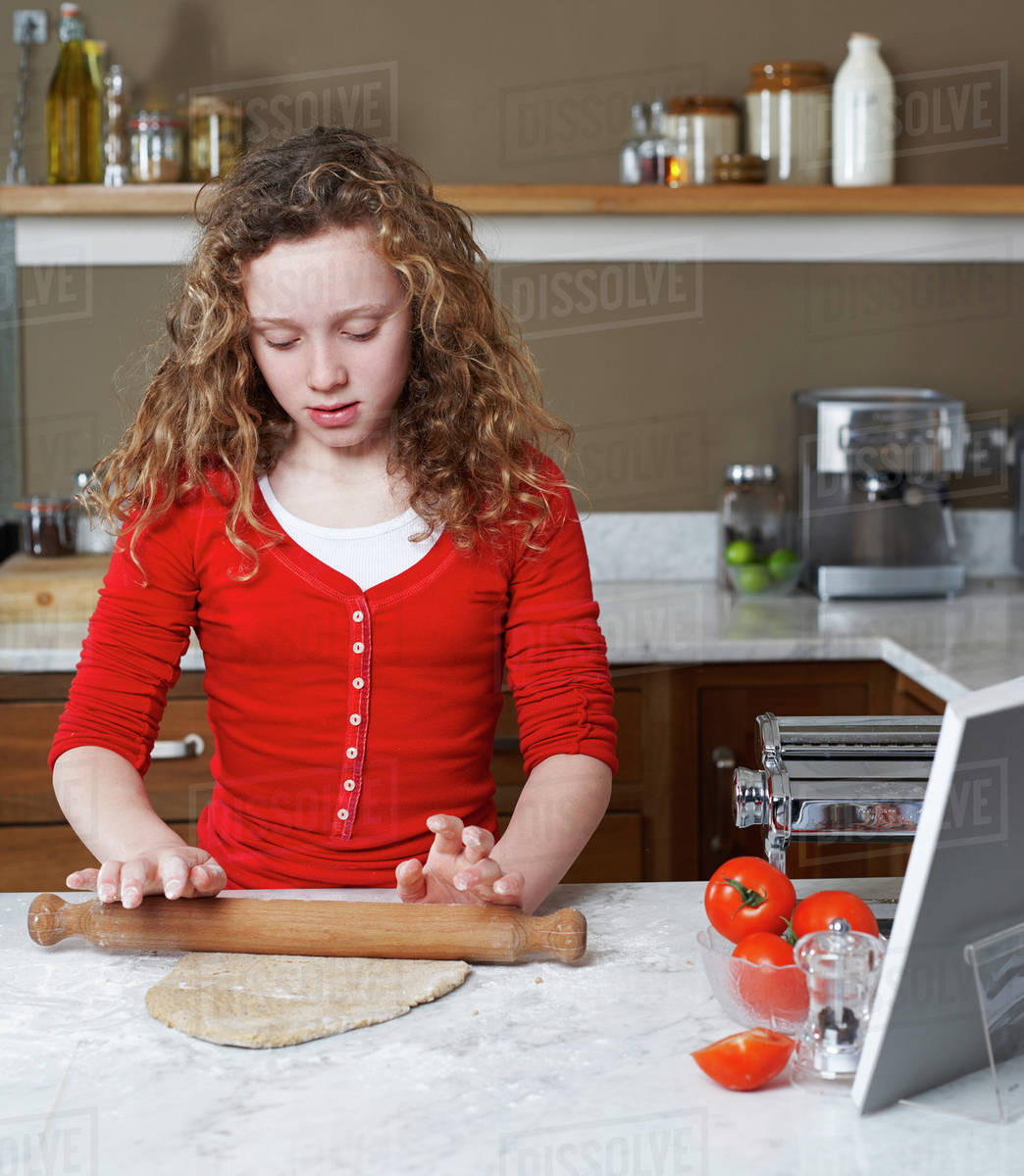 Girl rolling dough in kitchen Stock Photo Dissolve