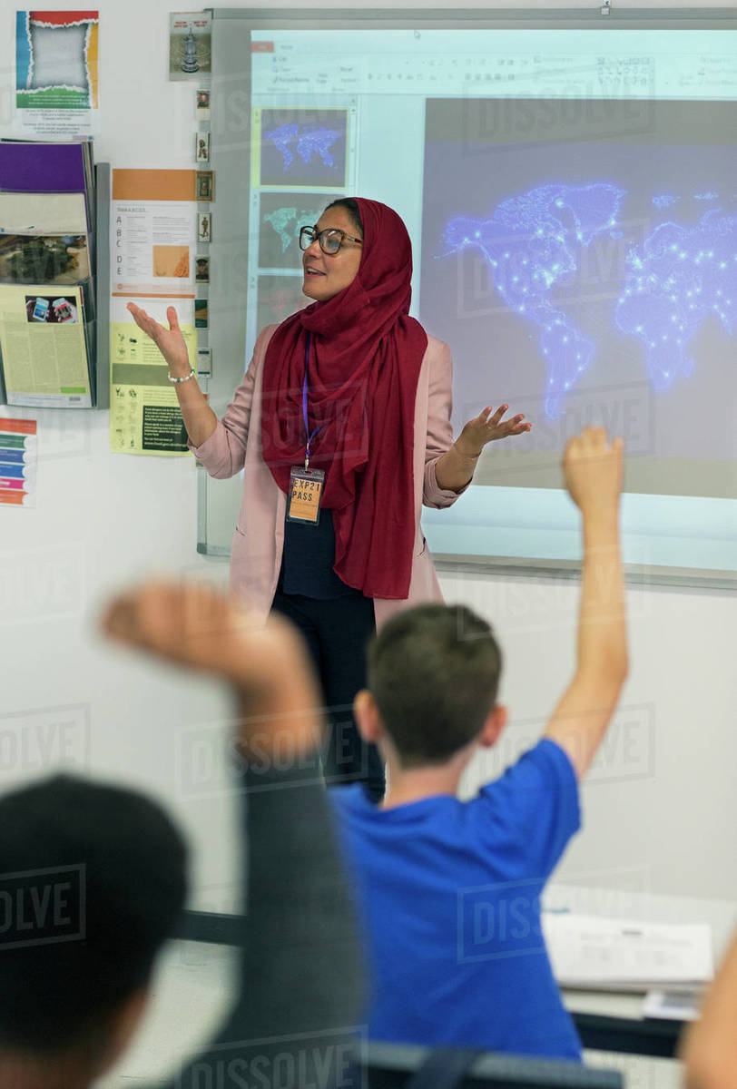 Female teacher in hijab leading lesson at projection screen in classroom Royalty-free stock photo