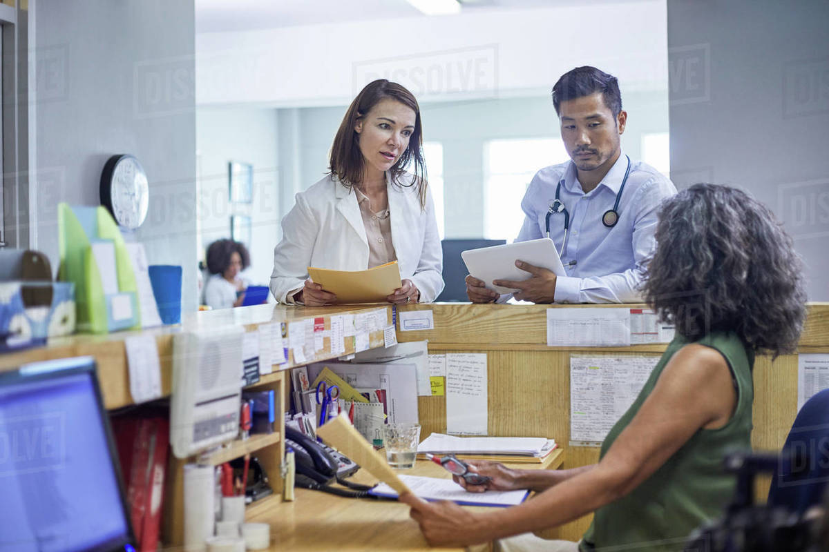 Doctors And Receptionist Talking In Clinic Stock Photo Dissolve