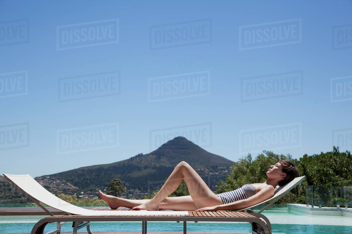 Woman sunbathing lounge chair poolside Stock Photo Dissolve