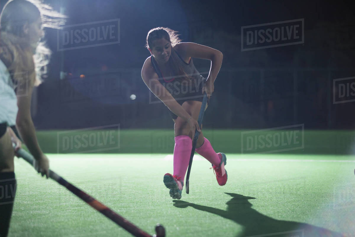 Determined young female field hockey player running with hockey stick