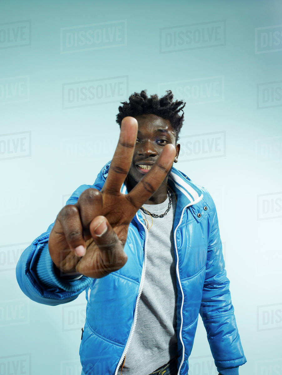 A hip young man flashing the peace sign, focus on hand Stock Photo