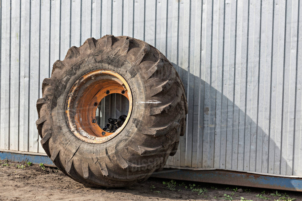 Construction vehicle wheel leaning against industrial building Stock Photo Dissolve