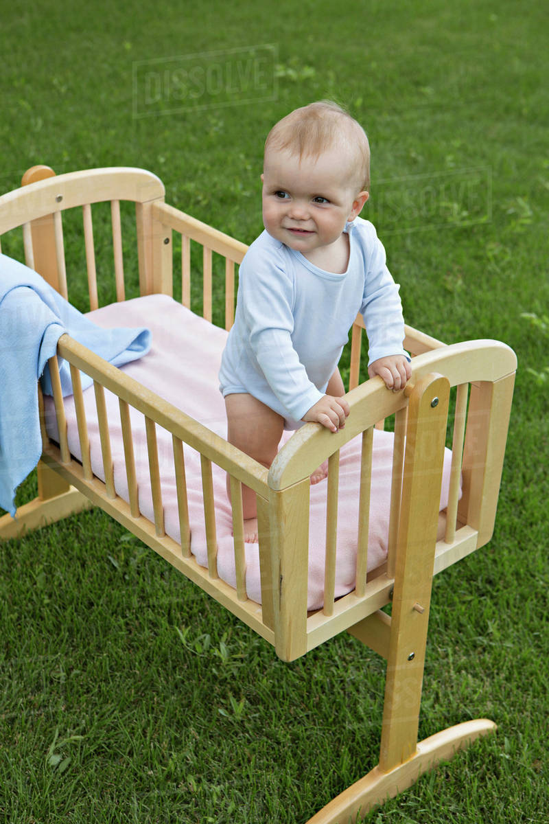 Baby standing in cot outside Stock Photo Dissolve