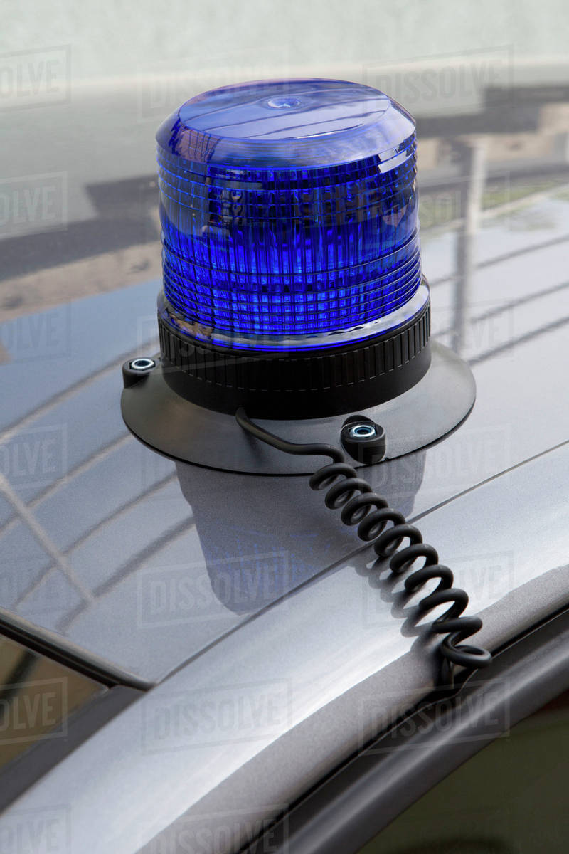A blue emergency light on the roof of a police car Stock Photo Dissolve