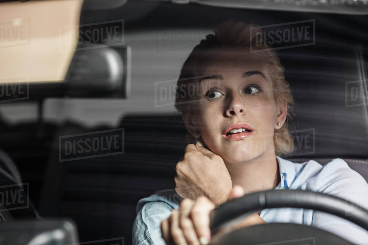 Mid adult woman looking in rearview mirror while driving car Stock