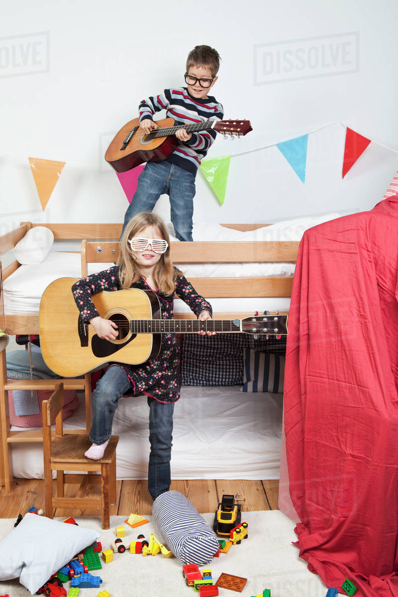 Two children playing with guitars in a child's playroom Stock Photo