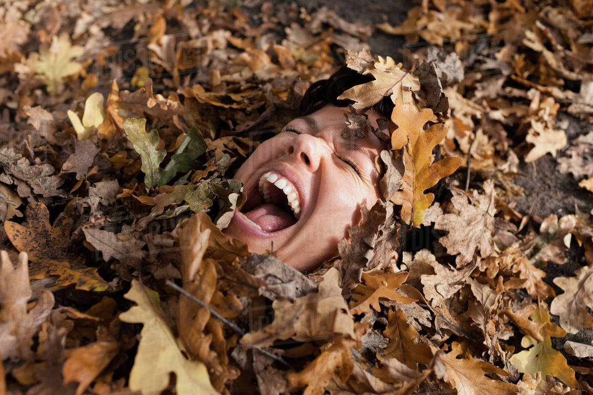 Closeup of woman shouting with closed eyes covered in dry leaves