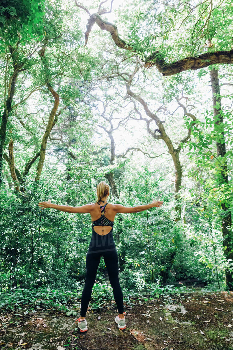 Fit female personal trainer exercising, stretching arms in forest Royalty-free stock photo