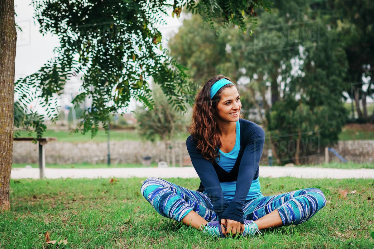 Smiling, fit female trainer exercising, stretching in park Royalty-free stock photo