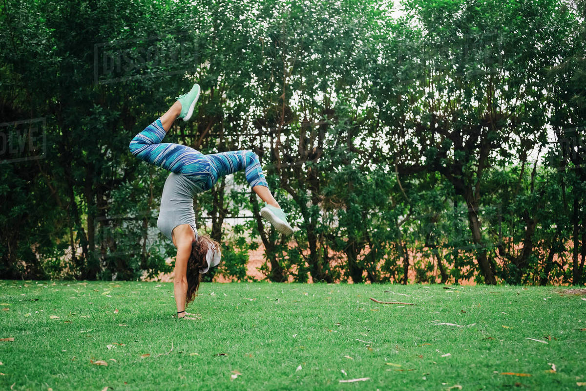 Fit, carefree female personal trainer doing handstand in park Royalty-free stock photo