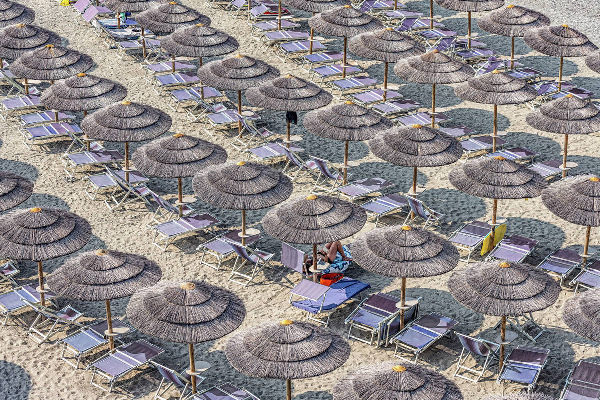 Straw beach umbrellas and lounge chairs on tourist resort beach, Varazze, Liguria, Italy Royalty-free stock photo
