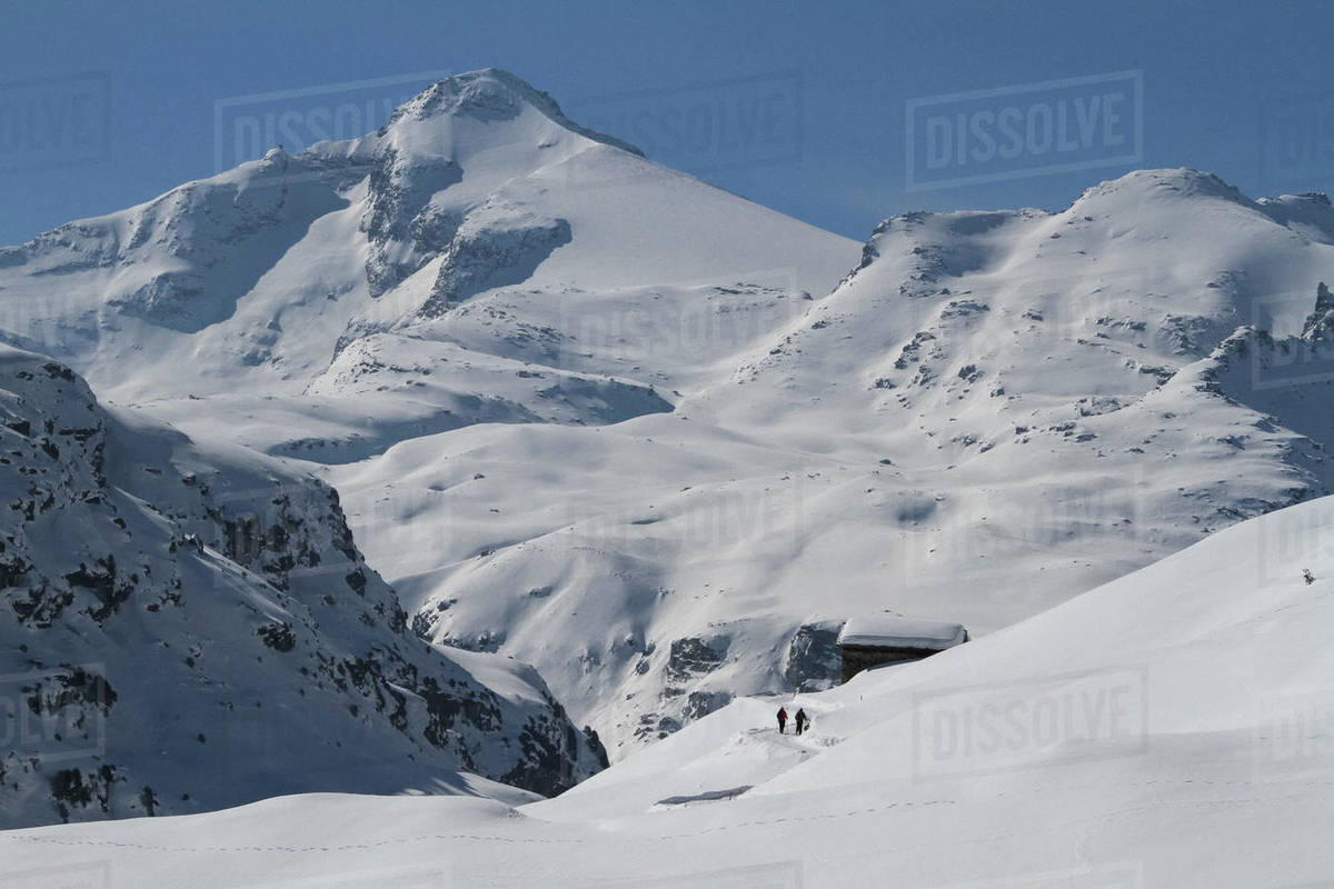 People walking toward cabin on remote, snow covered mountain, Vals, Canton of Grisons, Switzerland Royalty-free stock photo