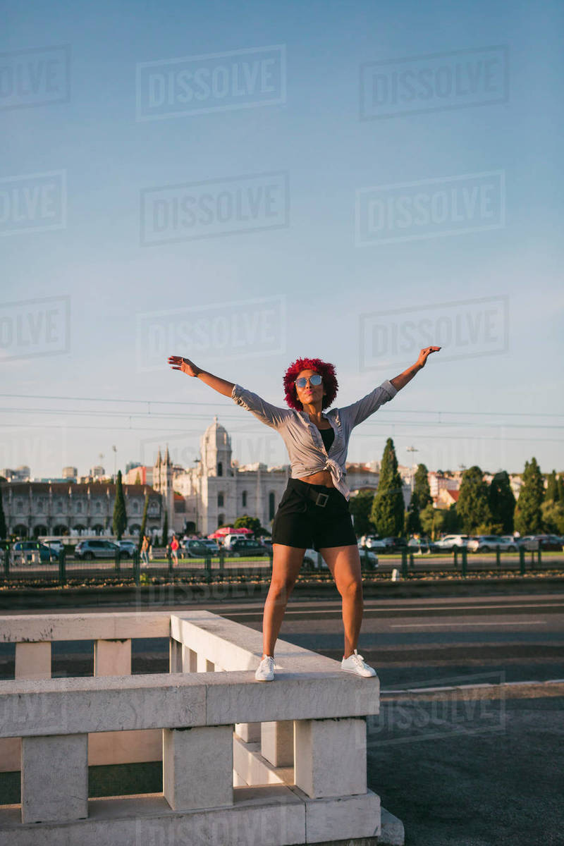 Portrait confident, carefree woman on building ledge with Jeronimos Monastery in background, Lisbon Royalty-free stock photo