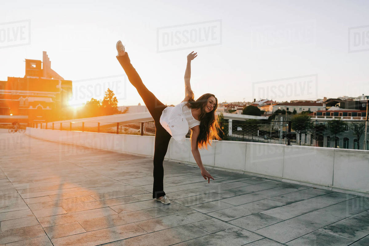 Playful young female dancer doing standing splits in sunny city park Royalty-free stock photo