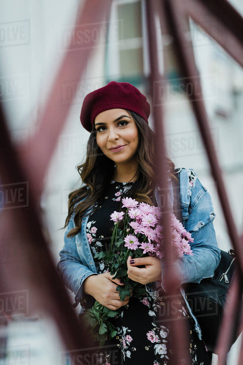 Portrait confident young woman in beret holding flower bouquet Royalty-free stock photo