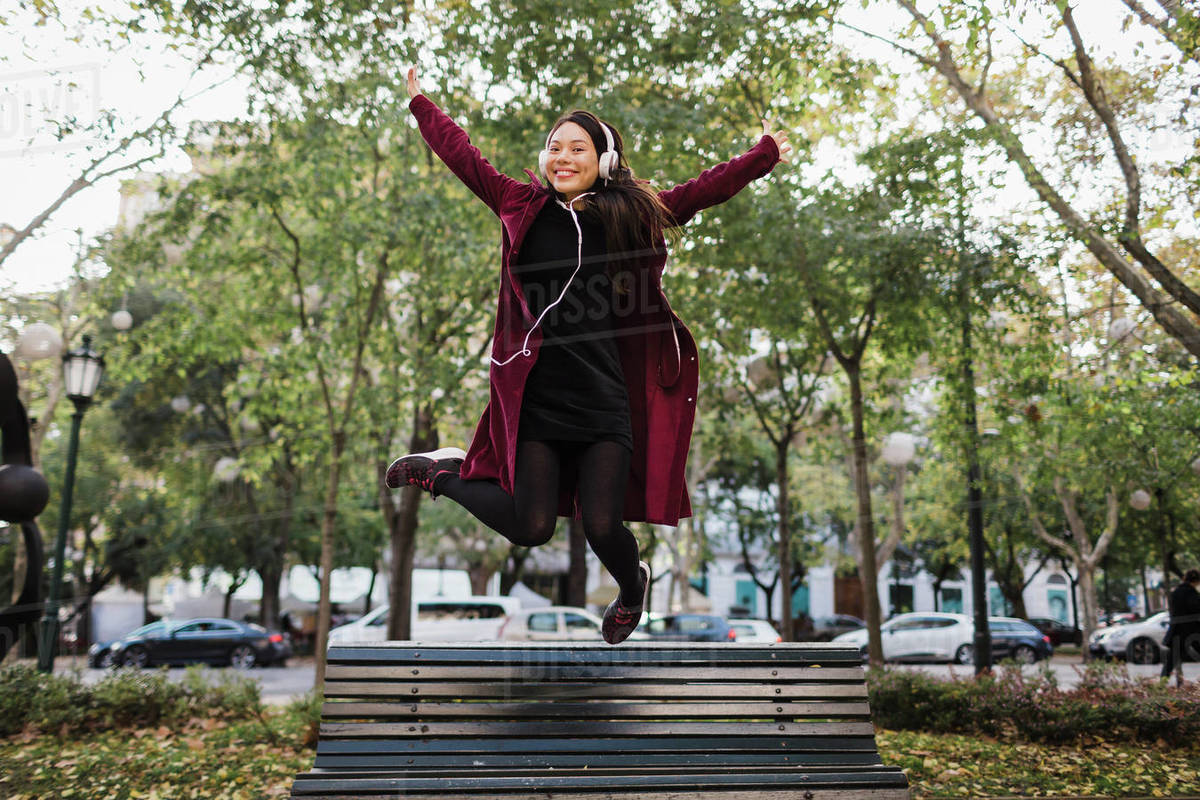 Portrait playful exuberant woman jumping off urban city bench Royalty-free stock photo