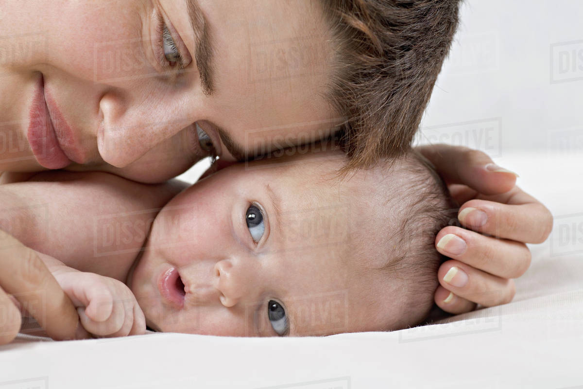 A mother cuddling a baby lying on its stomach Stock Photo Dissolve